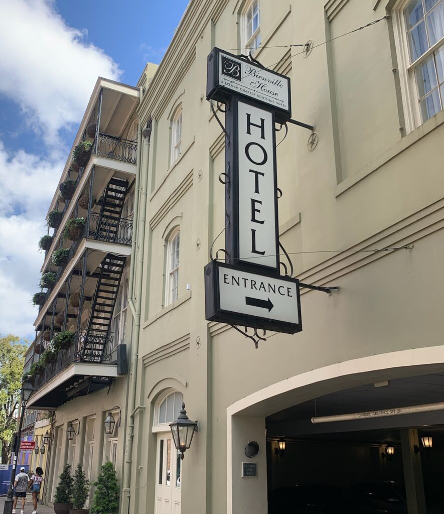 A hotel entrance sign hanging off a building