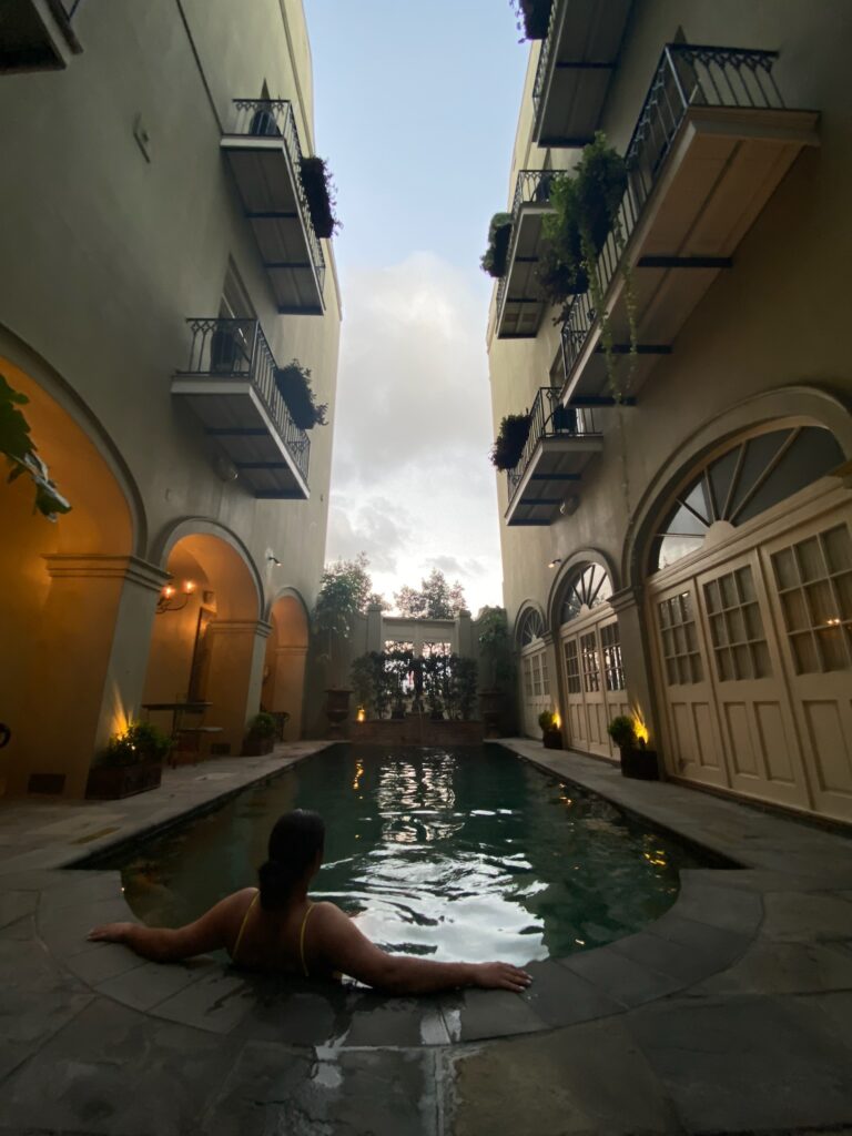 Female sitting on the edge of a pool looking up to an alley of balconies.