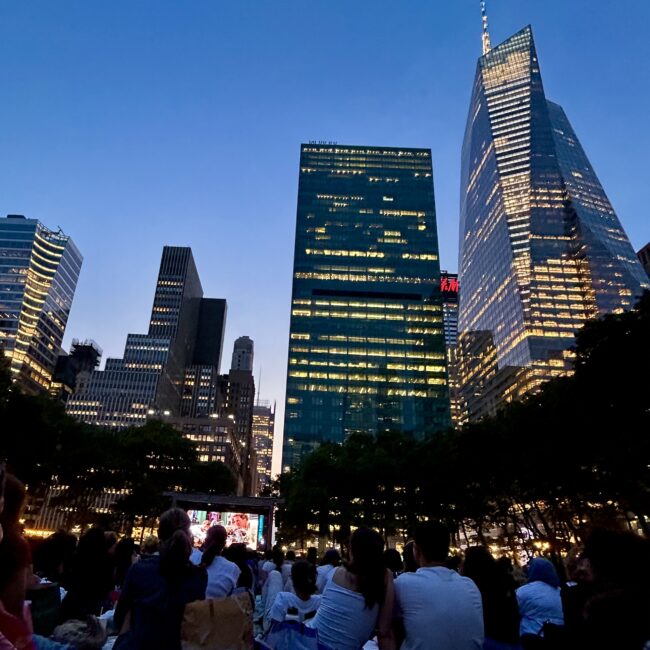 NYC skyscrapers with a giant movie screen in the distance