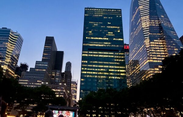 NYC skyscrapers with a giant movie screen in the distance