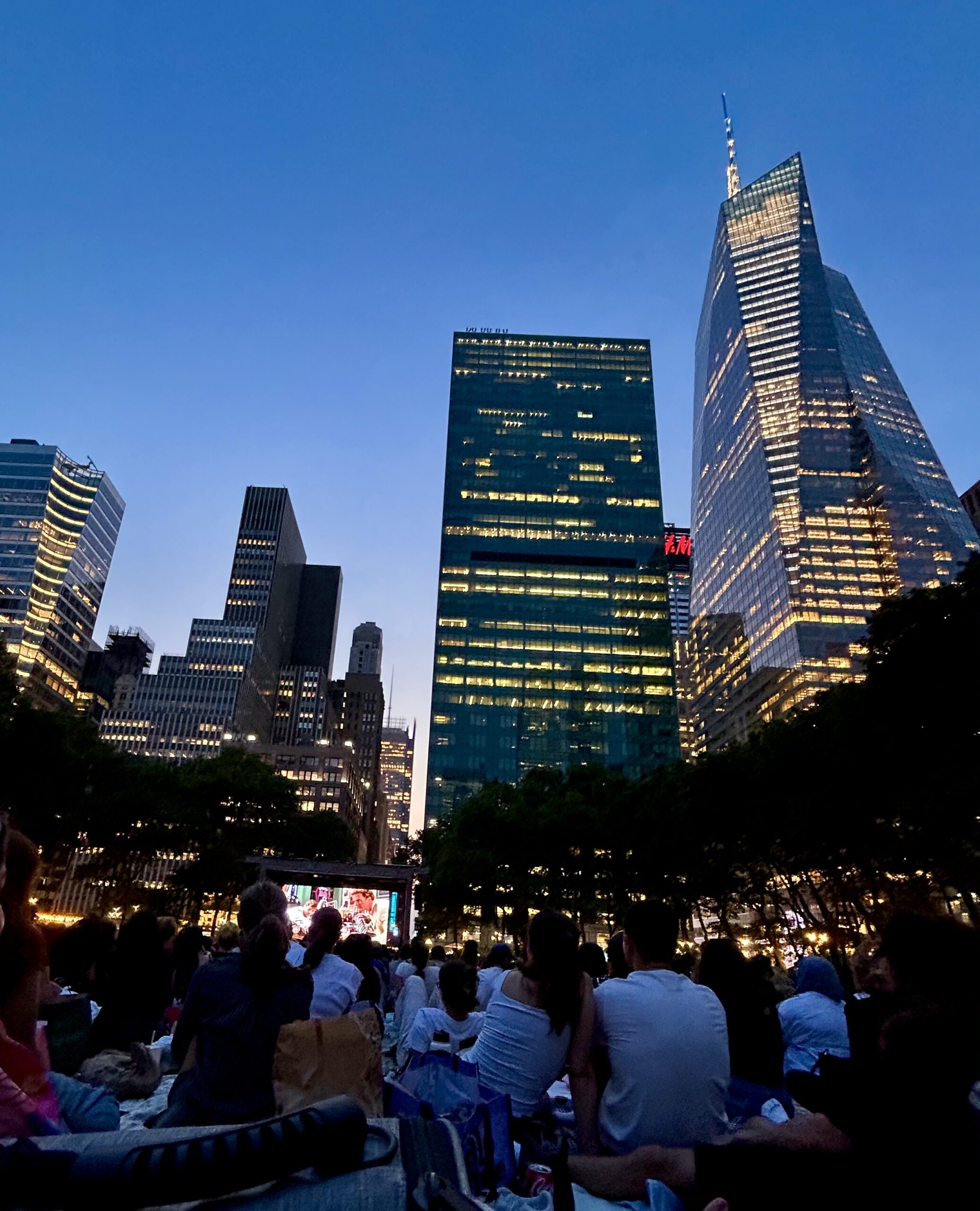 NYC skyscrapers with a giant movie screen in the distance