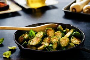 Brussels sprouts sizzling in a cast iron skillet, showcasing a healthy and rustic cooking method.