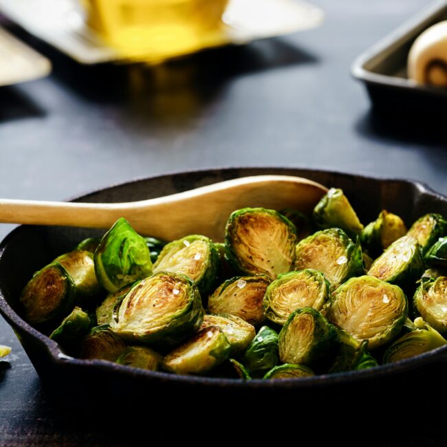 Brussels sprouts sizzling in a cast iron skillet, showcasing a healthy and rustic cooking method.