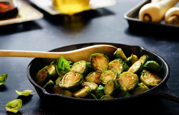 Brussels sprouts sizzling in a cast iron skillet, showcasing a healthy and rustic cooking method.