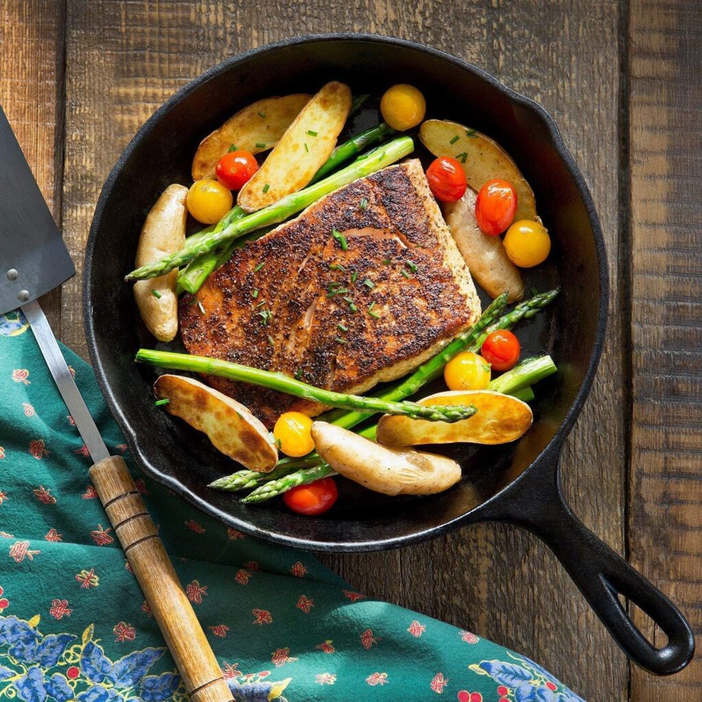 Fish being cooked in a cast iron skillet on a counter top